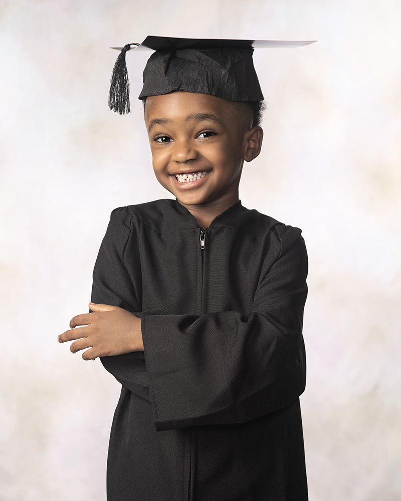 Happy kindergarten graduate in robes by Dan Cleary of Cleary Creative Photography
