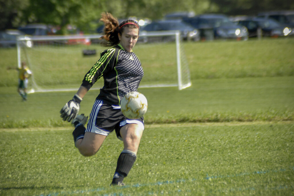 photograph of female high school soccer player kicking the ball